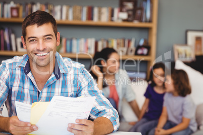 Happy man wih documents while family sitting in background