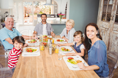 Smiling family with grandparents sitting at dining table