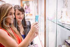 Two women taking a photo of shop display