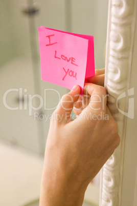 Woman sticking I love you note on mirror