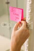 Woman sticking I love you note on mirror