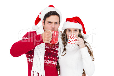 Happy couple with santa hats drinking a hot beverage