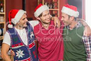 Friends with Christmas hats smiling at each other