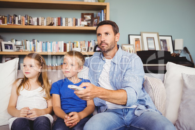 Family watching television while sitting on sofa