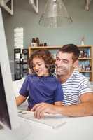 Cheerful father and son using computer at home