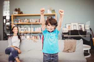 Smiling boy wearing superhero costume with mother sitting on sof