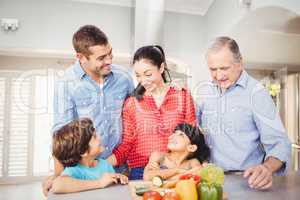 Cheerful family standing by kitchen table