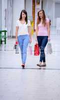 Two beautiful women walking in mall with shopping bags