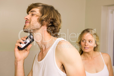 Handsome man about to shave with his girlfriend behind