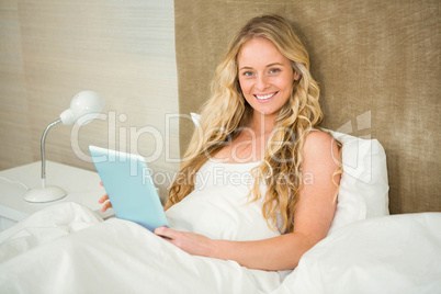 Pretty woman using tablet computer in her bed