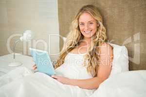 Pretty woman using tablet computer in her bed