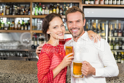 Couple smiling at camera and holding beers