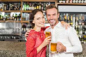 Couple smiling at camera and holding beers