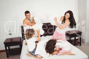 Cheerful family pillow fighting on bed