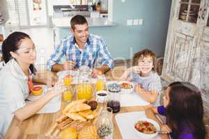 Happy family eating breakfast at table in house