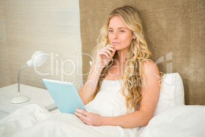 Pretty woman using tablet computer in her bed