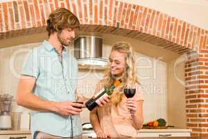 Cute couple enjoying a glass of wine and reading the bottle