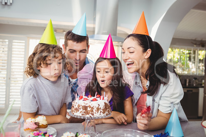 Cheerful children blowing candles on birthday cake