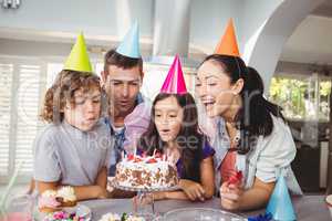Cheerful children blowing candles on birthday cake