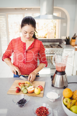 Smiling woman cutting fruits