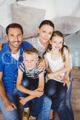 Portrait of happy family sitting by sofa