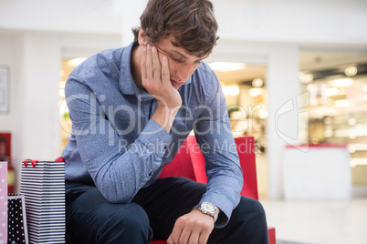 Tired man sitting in shopping mall