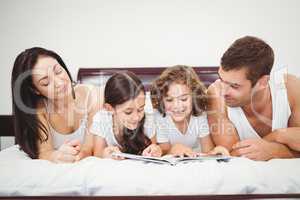 Children reading book with parents at home