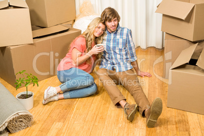 Cute couple sitting on the floor while drinking