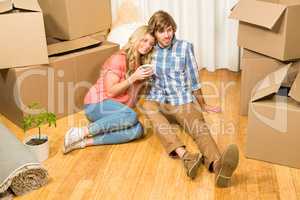 Cute couple sitting on the floor while drinking