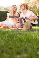 Happy couple having a picnic and playing guitar