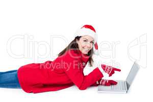 Brunette with santa hat lying on the floor pointing her laptop