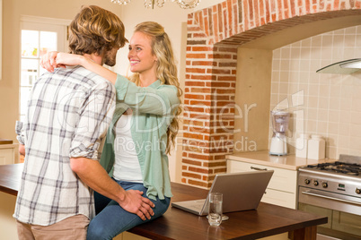 Cute couple cuddling with girlfriend sitting on the counter