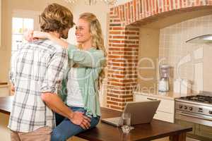 Cute couple cuddling with girlfriend sitting on the counter