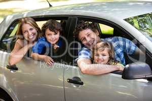 Smiling family sitting in a car