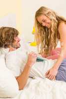 Cute couple cuddling in their bed and reading a book