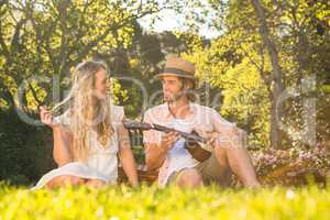 Happy couple having a picnic and playing guitar