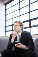 Thoughtful businessman sitting on sofa and looking away