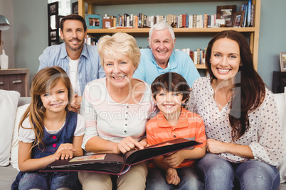 Portrait of smiling family with grandparents holding photo album