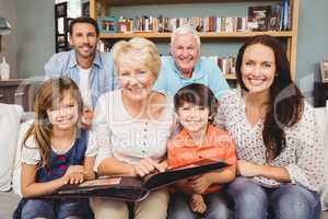 Portrait of smiling family with grandparents holding photo album