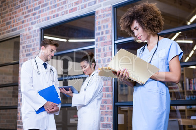 Female doctor checking a file near library