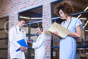 Female doctor checking a file near library