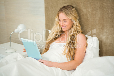 Pretty woman using tablet computer in her bed