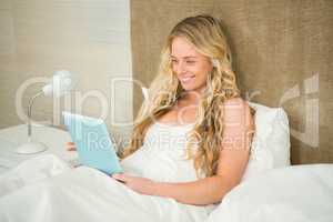 Pretty woman using tablet computer in her bed