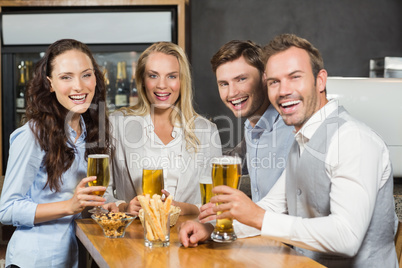 Friends smiling at camera with beers in hand