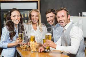 Friends smiling at camera with beers in hand