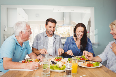 Family laughing while sitting at dining table