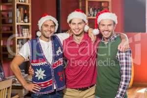 Friends with Christmas hats smiling at camera