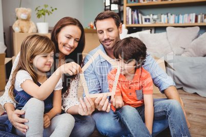 Smiling family holding house shape at home