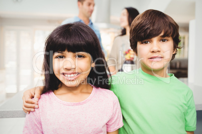 Portrait of smiling siblings standing at table