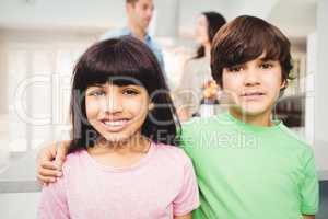 Portrait of smiling siblings standing at table